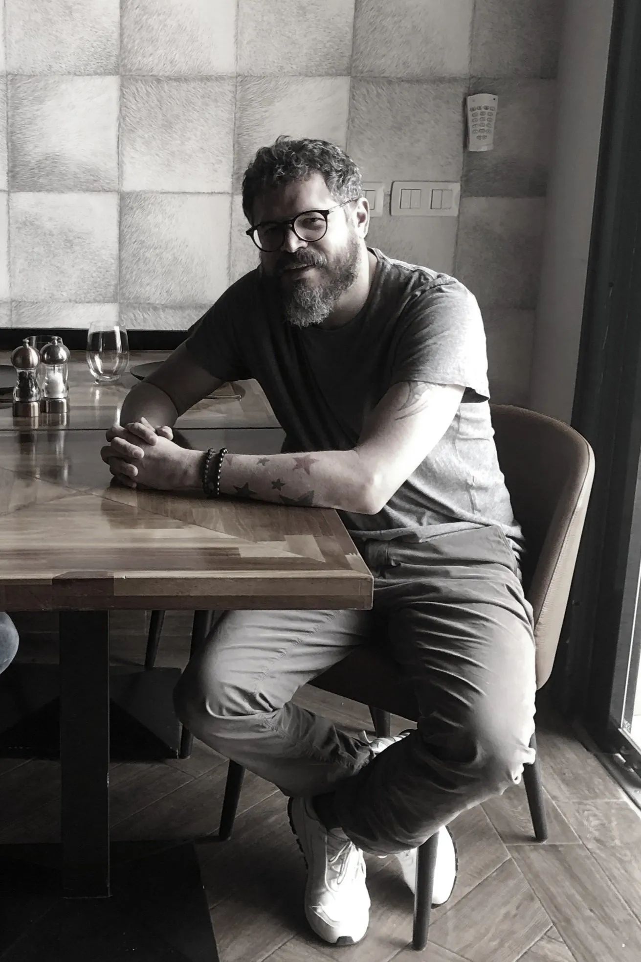John Guerrero sonriendo, sentado a la mesa de madera de un restaurante