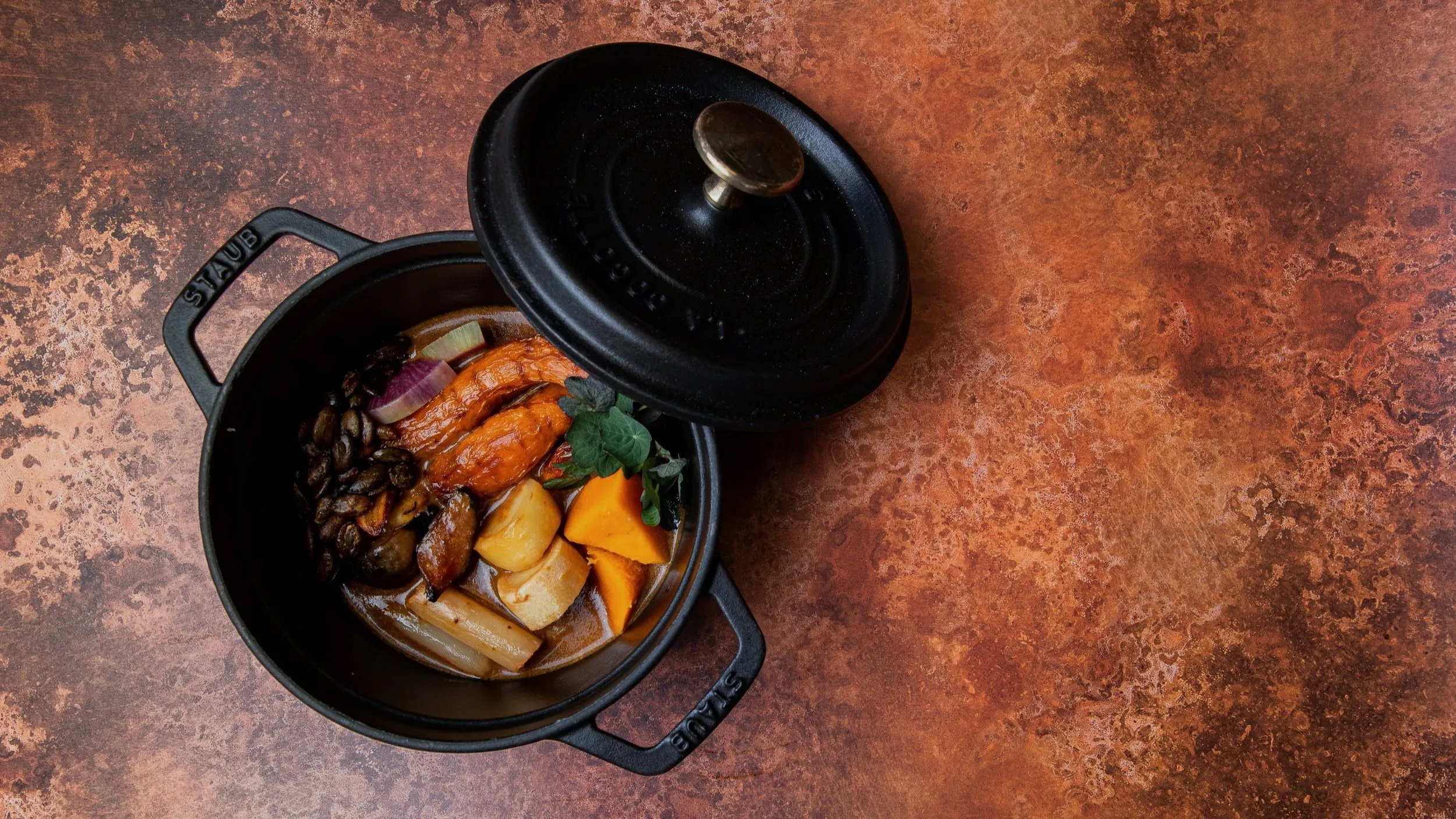 Cocotte de hierro fundido con verduras asadas de temporada vista desde arriba