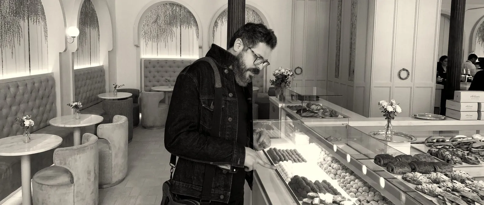 El Chef John Guerrero, con chaqueta vaquera, eligiendo dulces frente al mostrador de una pastelería elegante